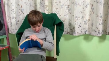 Okul çağındaki çocuk evde ders çalışıyor, ödevlerini özveriyle yapmaya odaklanmış. Öğrenmeyi destekleyen sakin bir ortamda okuma ve sayma, bilgi ve beceriler geliştirme pratiği yapıyor.. 