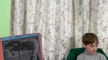 Okul çağındaki çocuk evde ders çalışıyor, ödevlerini özveriyle yapmaya odaklanmış. Öğrenmeyi destekleyen sakin bir ortamda okuma ve sayma, bilgi ve beceriler geliştirme pratiği yapıyor.. 