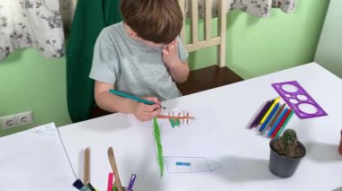 Evde kalemlerle resim çizen sevimli bir okul çocuğu. Yaratıcı bir işle uğraşıyor. Hobisine odaklanmış, evde boş vakit geçirirken hayal gücü ve sanatsal beceriler geliştiriyor.. 