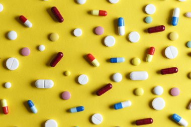 Sarı arka plana dağılmış farklı hap ve kapsüller, Tex için boşluk