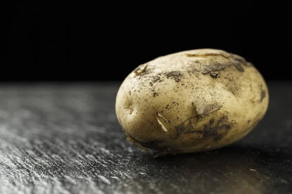 生在泥里的小土豆 躺在黑色的石板上背景 — 图库照片