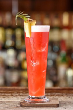 Singapore sling cocktail with gin, cherry and orange liqueur Benedict, grenadine, pineapple and lemon juice with the addition of bitter Angostura. Cocktail on the background of the bar in the nightclub clipart