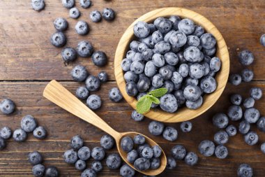 yaban mersini bir ahşap arka planda bir tabak ve kaşık, meyveler masanın üzerine dağılmış. abov görüntülemek