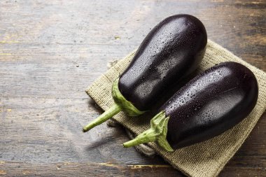 çuval bezi üzerinde yalan ahşap bir masa üzerinde iki Olgun patlıcan. tex için yer