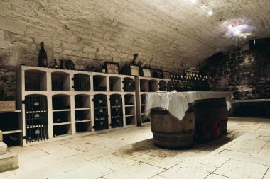 Şarap mahzeni, duvarlar boyunca odada tatma şarap şişeleri ile raflar vardır. Oda - tablolar varil şeklinde ortasında. Chablis, Fransa. 23 Temmuz 2017.