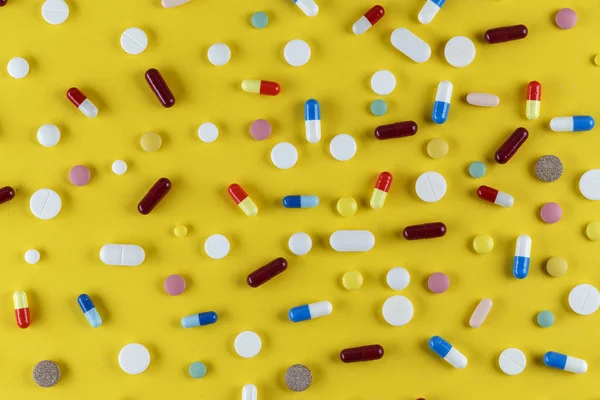 分散在黄色背景上的不同药丸和胶囊 空间为Tex — 图库照片