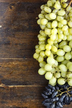 koyu ahşap arka plan üzerinde olgunlaşmış yeşil ve mavi üzüm demet. tex için yer