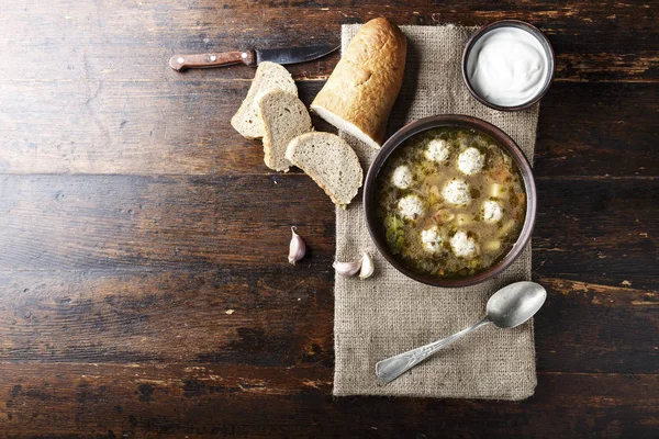 rustic home made soup with meatballs on a simple wooden background. useful and delicious homemade food
