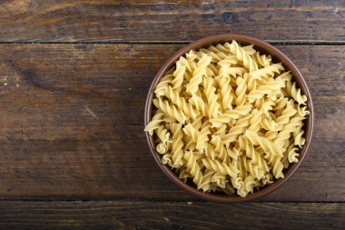 pişmemiş makarna bir tabak içinde bir huş ağacı kabuğu arka plan üzerinde spiral. tex için yer