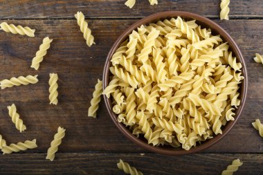 pişmemiş makarna bir tabak içinde bir huş ağacı kabuğu arka plan üzerinde spiral. tex için yer