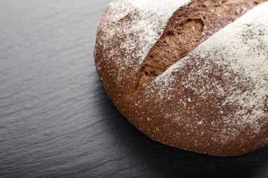 bir somun siyah arduvaz arka plan üzerinde siyah yuvarlak ekmek. tex için yer