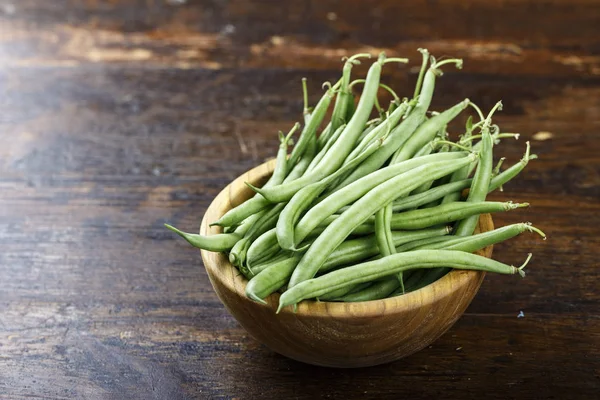 green asparagus beans on a wooden background in a wooden treble. space for tex