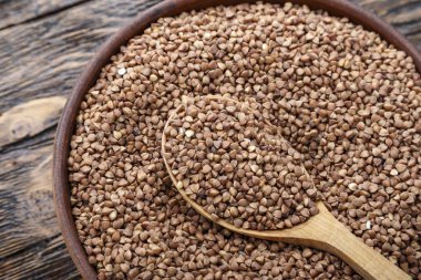 karabuğday kabuğu çıkarılmış tane ahşap bir masa üzerinde bir tabak içinde. tahta kaşık bir tabak içinde. tex için alan