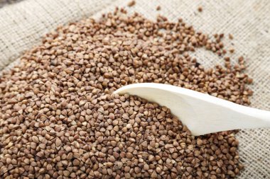 karabuğday kabuğu çıkarılmış tane ahşap bir masa üzerinde dağınık. çul bir tahta kaşık yakınındaki üzerinde Mısır gevreği. tex için alan