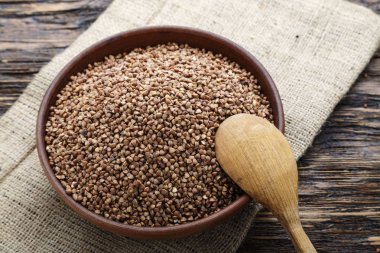 karabuğday kabuğu çıkarılmış tane ahşap bir masa üzerinde bir tabak içinde. tahta kaşık bir tabak içinde. tex için alan