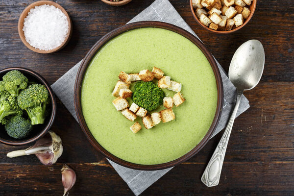 broccoli cream soup in a plate on the table. beside spoon and spice