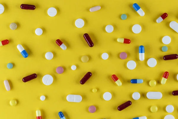 分散在黄色背景上的不同药丸和胶囊 空间为Tex — 图库照片