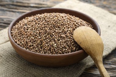 ahşap arka plan üzerinde bir kil plaka ham karabuğday kabuğu çıkarılmış tane. tahta kaşık plaka. tex için alan