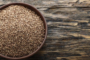 ahşap arka plan üzerinde bir kil plaka ham karabuğday kabuğu çıkarılmış tane. tex için alan