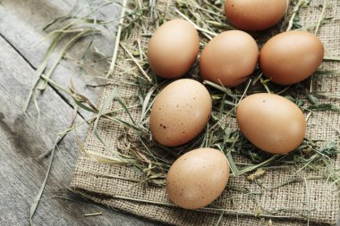 masanın üzerine çuval bezi üzerinde çiğ tavuk yumurtası. saman masanın üzerinde dağınık olduğunu. rustik loo