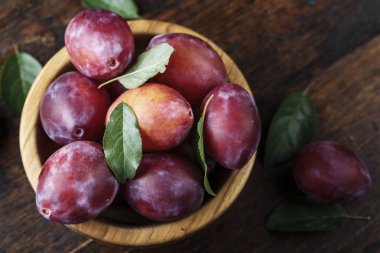 Olgun erik koyu kahverengi ahşap bir masa üzerinde bir ahşap plaka. rustik tarzı
