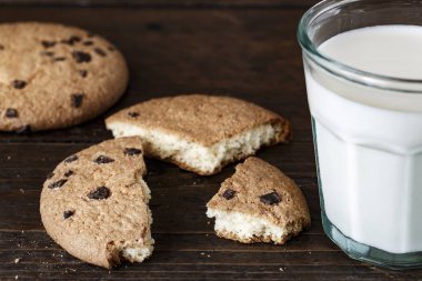 Çikolatalı kurabiye ve taze bir bardak süt karanlık bir tablo.