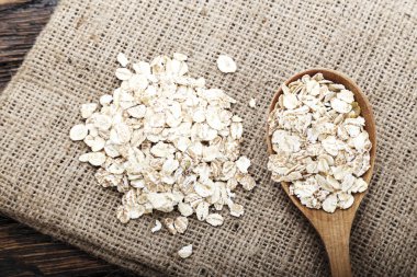bir çuval bezi üzerinde bir tahta kaşık çiğ yulaf gevreği. Sağlıklı karbonhidrat kahvaltı. tex için alan