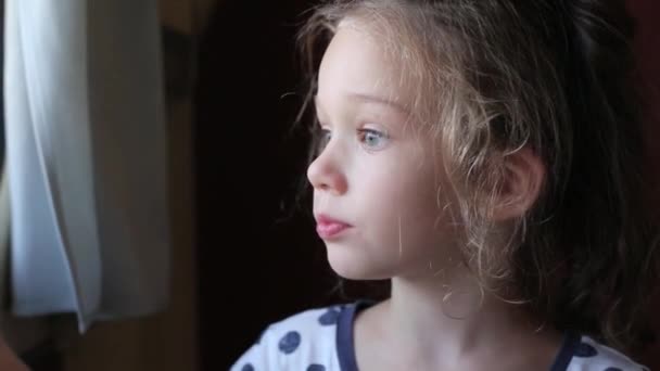 Little girl looks out the window — Stock Video