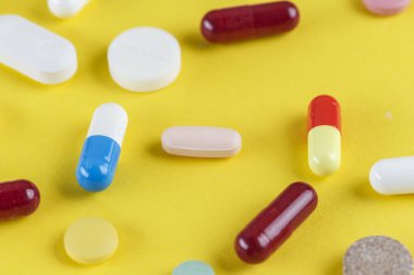 Sarı arka plana dağılmış farklı hap ve kapsüller, Tex için boşluk