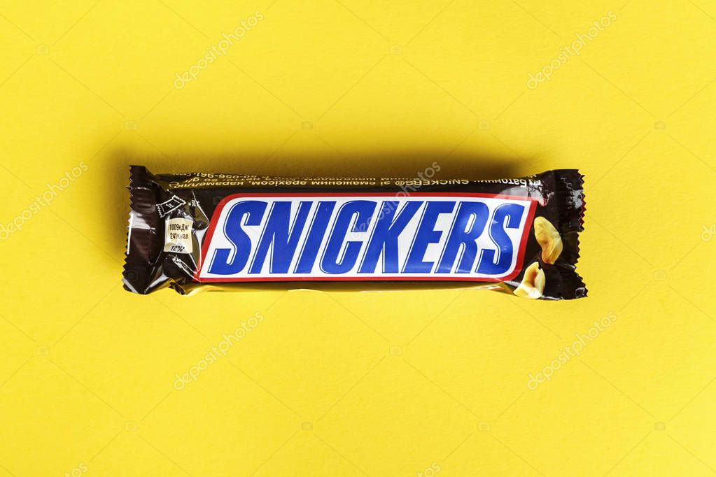Ukraine, Kiev March 29, 2018. Chocolate Snickers on a yellow background. Snickers bars are produced by Mars Incorporated.