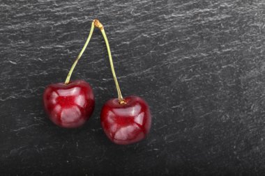 İki kırmızı tatlı kiraz siyah bir arka plan tutamacı. tex için alan