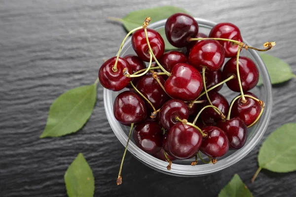 Red sweet cherries in a plate on a black background. space for tex