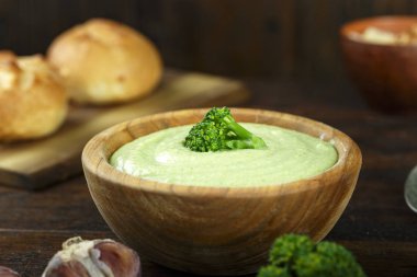 Kremalı brokoli çorbası bir plaka üzerinde koyu ahşap arka plan. bir tas çorba yanında taze ekmeği vardır. top vie