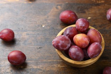Olgun kırmızı erik bir plaka üzerinde eski püskü ahşap arka plan. metin için yer