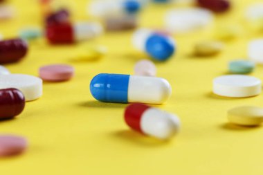 Sarı arka plana dağılmış farklı hap ve kapsüller, Tex için boşluk