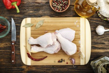 Ahşap adam üzerinde kesme tahtası üzerinde baharatlar ile çiğ tavuk budu