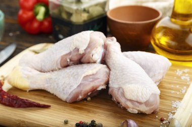 Ahşap adam üzerinde kesme tahtası üzerinde baharatlar ile çiğ tavuk budu