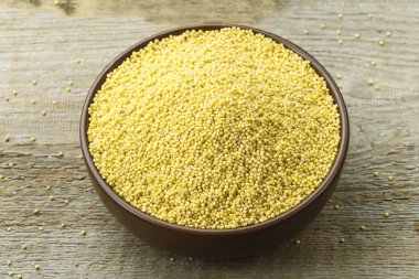 Eski püskü ahşap arka plan üzerinde bir kil plaka ham darı kabuğu çıkarılmış tane. tex için alan