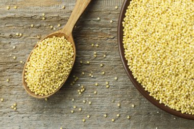 Eski püskü ahşap arka plan üzerinde bir kil plaka ham darı kabuğu çıkarılmış tane. tex için alan