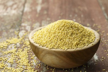 Eski püskü ahşap arka plan üzerinde bir ahşap plaka ham darı kabuğu çıkarılmış tane. metin için yer