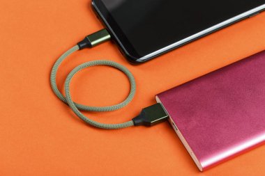 belgili tanımlık smartphone üzerinde sarı bir adam bir pembe güç bankadan şarj