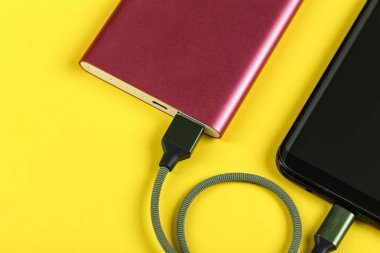 belgili tanımlık smartphone üzerinde sarı bir adam bir pembe güç bankadan şarj