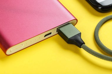 belgili tanımlık smartphone üzerinde sarı bir adam bir pembe güç bankadan şarj