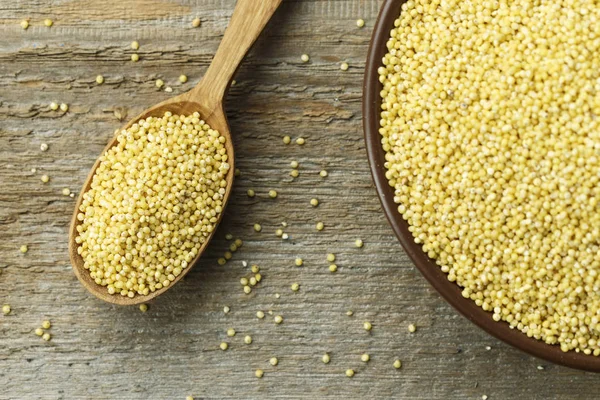 Eski püskü ahşap arka plan üzerinde bir kil plaka ham darı kabuğu çıkarılmış tane. tex için alan