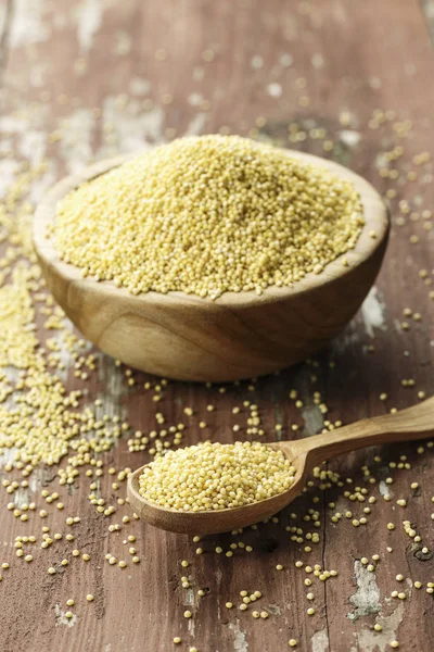 Eski püskü ahşap arka plan üzerinde bir ahşap plaka ham darı kabuğu çıkarılmış tane. metin için yer