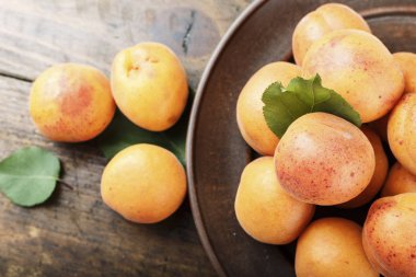 Ahşap arka plan üzerinde bir kil plaka yapraklarla olgun kayısı. tex için alan