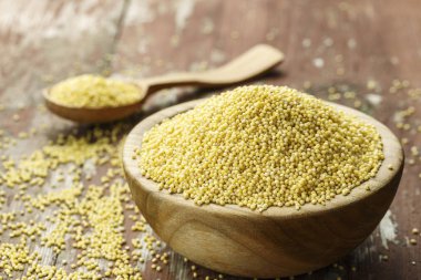 Eski püskü ahşap arka plan üzerinde bir ahşap plaka ham darı kabuğu çıkarılmış tane. metin için yer