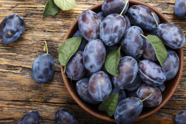 olgun erik bir kil plaka eski püskü ahşap arka plan üzerinde. tex için alan