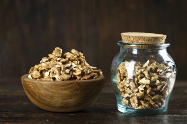 kahverengi ahşap arka plan üzerinde bir kavanoz içinde bir masada kıyılmış ceviz. tex için alan