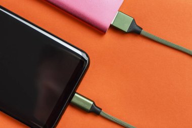 belgili tanımlık smartphone üzerinde sarı bir adam bir pembe güç bankadan şarj